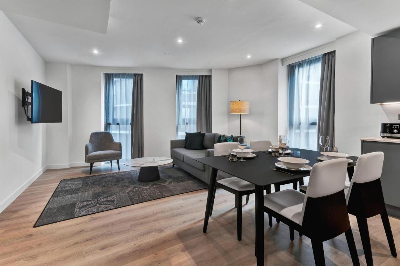 Citysuites 2 Aparthotel Mánchester Exterior foto The photo shows a modern living space that includes a living area and dining area. 

- **Living Area**: There's a gray sofa with a coffee table in front of it, along with a single armchair. A large flat-screen TV is mounted on the wall. The space is 