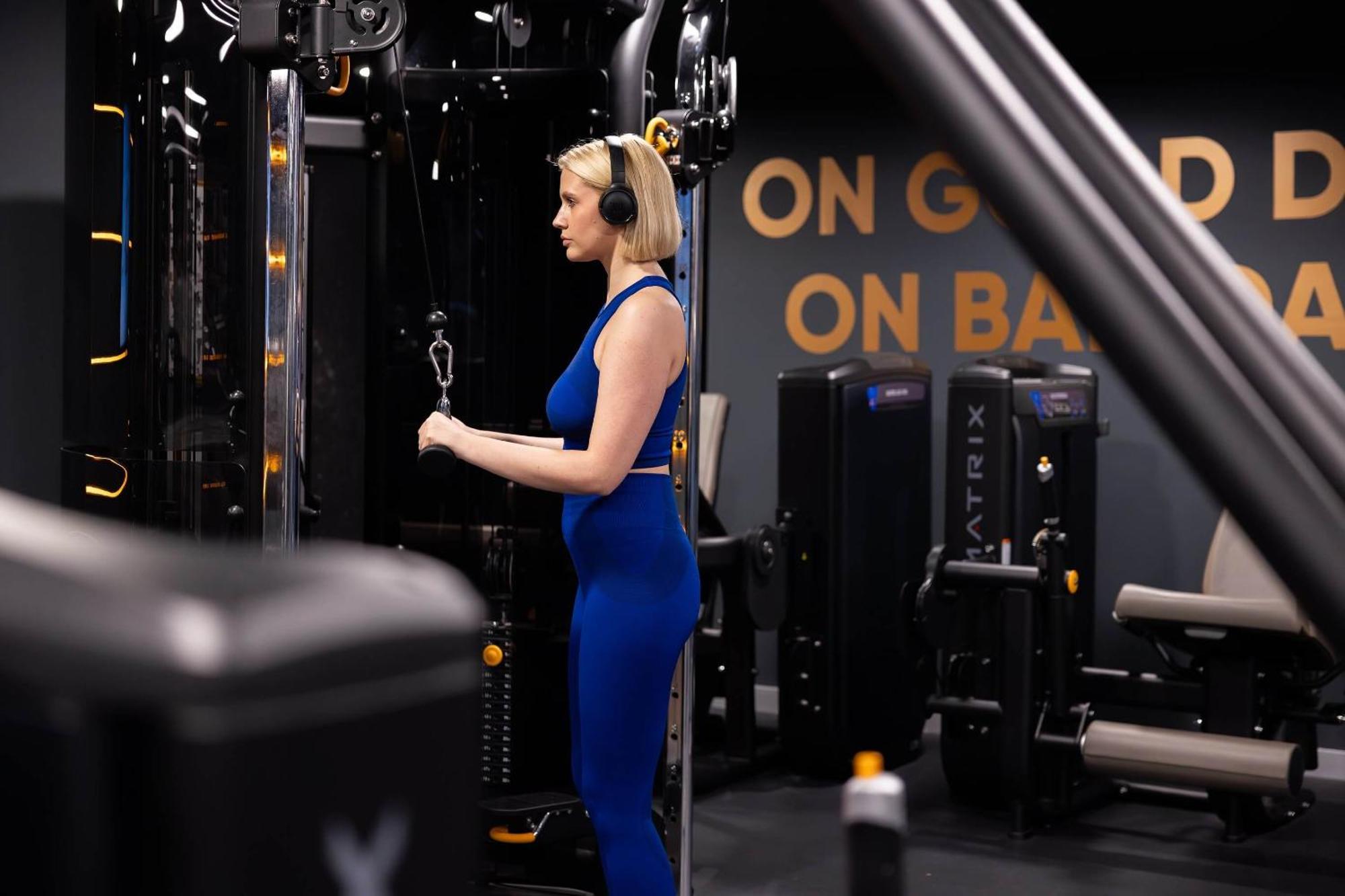 Citysuites 2 Aparthotel Mánchester Exterior foto The photo shows a woman working out in a gym. She is wearing a blue athletic outfit and headphones while using a gym machine. The background features various other gym equipment and a wall with the words "ON GOOD ON BAD" displayed prominently. The se